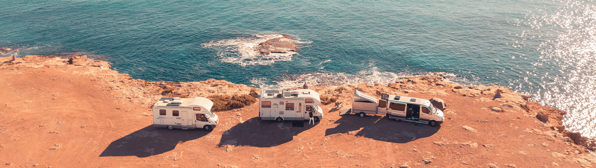Foto: drie campers op de rotsen aan zee